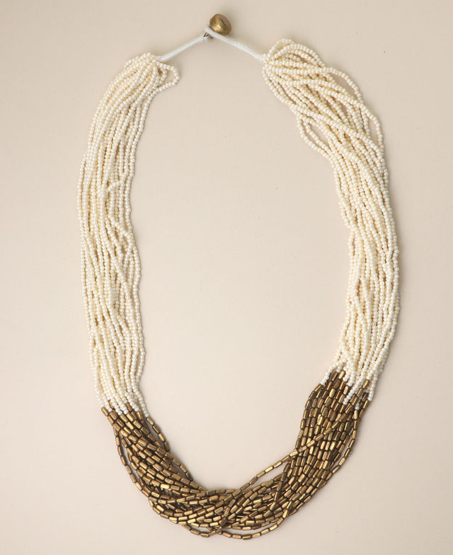 Multi-strand brass and glass bead necklace on beige background