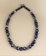 Deep blue ceramic bead necklace with abstract and floral designs.