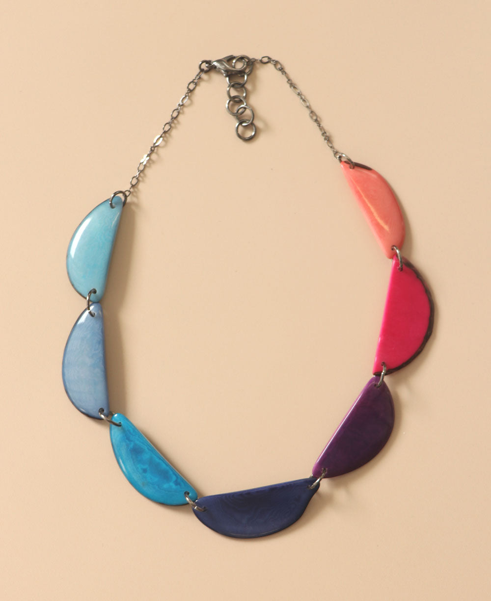 Colorful crescent-shaped Tagua necklace on beige background